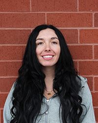 Carly Carlton, Recreation Manager, standing against a brick wall smiling