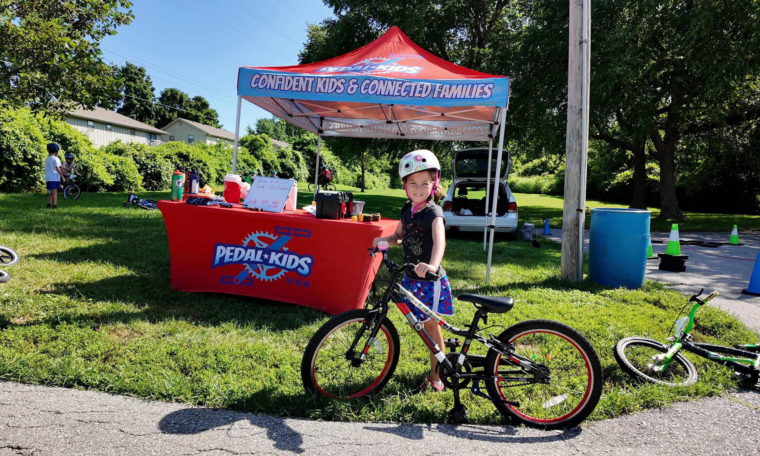 Kid with bike standing in front of a pop up pedal kids tent